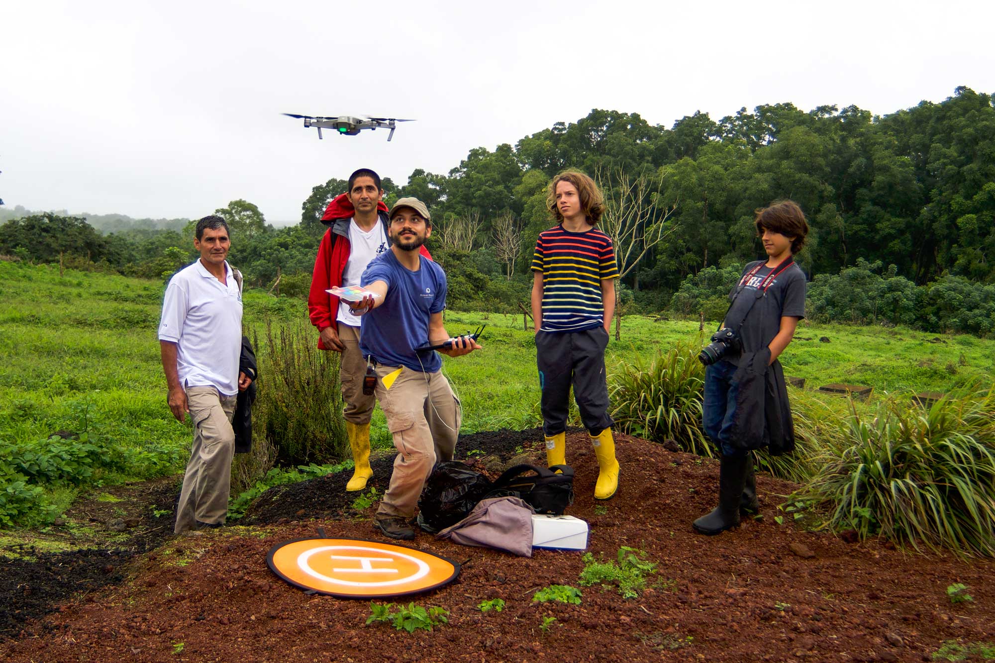 Five researchers stand in a field around a drone, the middle researcher launching the drone into the air.