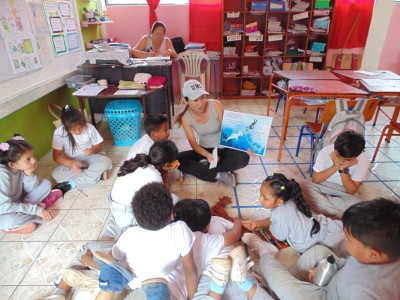 Leidy Apolo reads a picture book to a group of children.