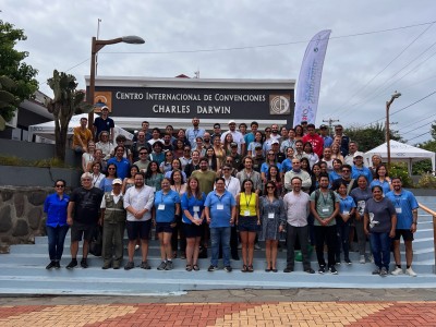 A large group of people standing outside on stairs in front of a sign reading 'Centro Internacional De Conveniones Charles Darwin.'