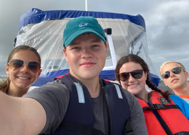 Selfie of Jonathan Collins and three other students on a boat.