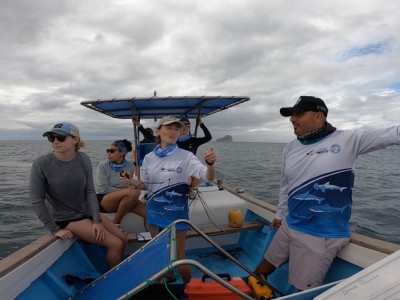 Savannah Ryburn gesturing while in a boat with 5 other researchers.