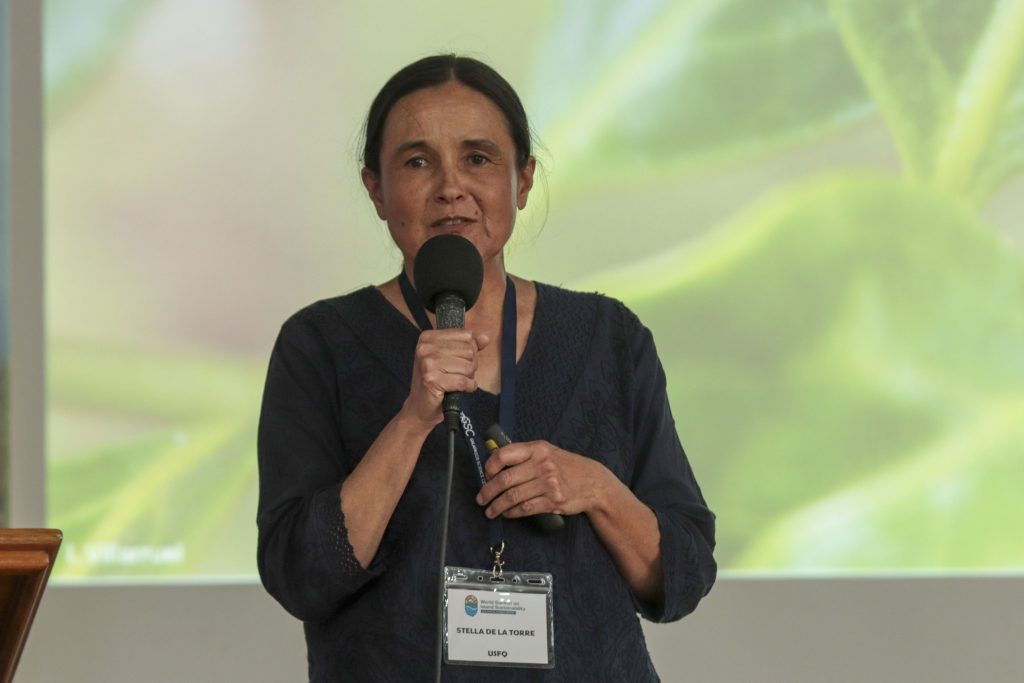Headshot of Stella De La Torre, speaking into a microphone